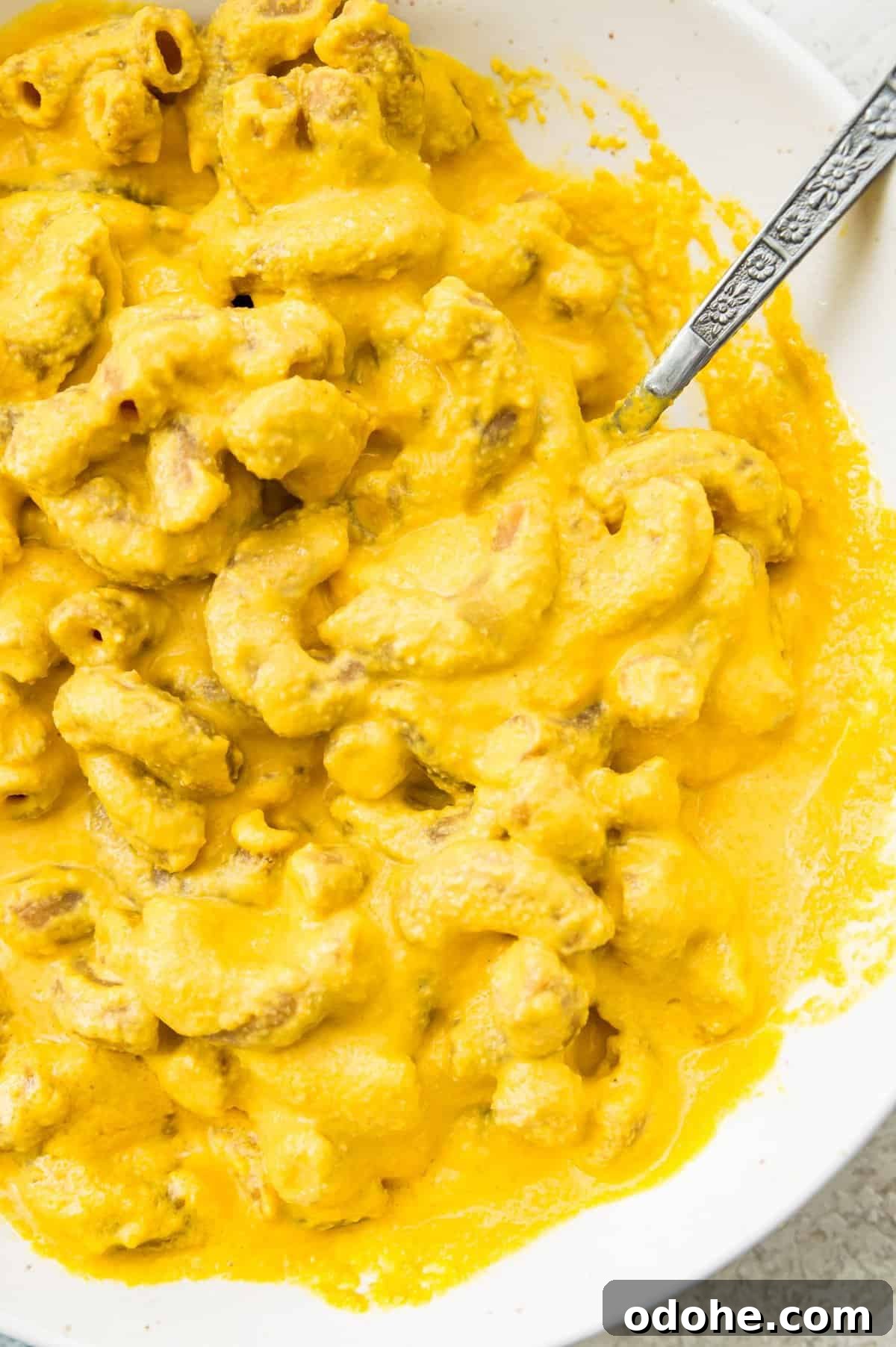 A bowl of dairy free Mac and cheese with a spoon in it.