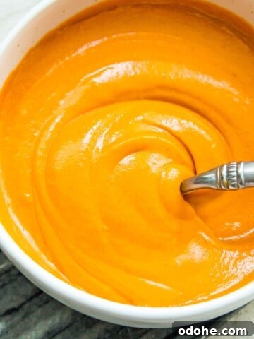A bowl of vegan buffalo sauce with a spoon in it.