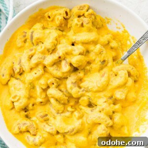 A bowl of dairy free Mac and cheese with a spoon in it.