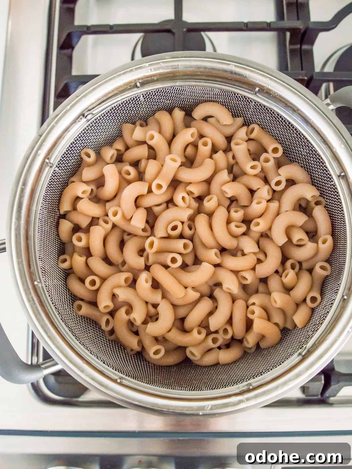 A colander with cooked noodles in it.
