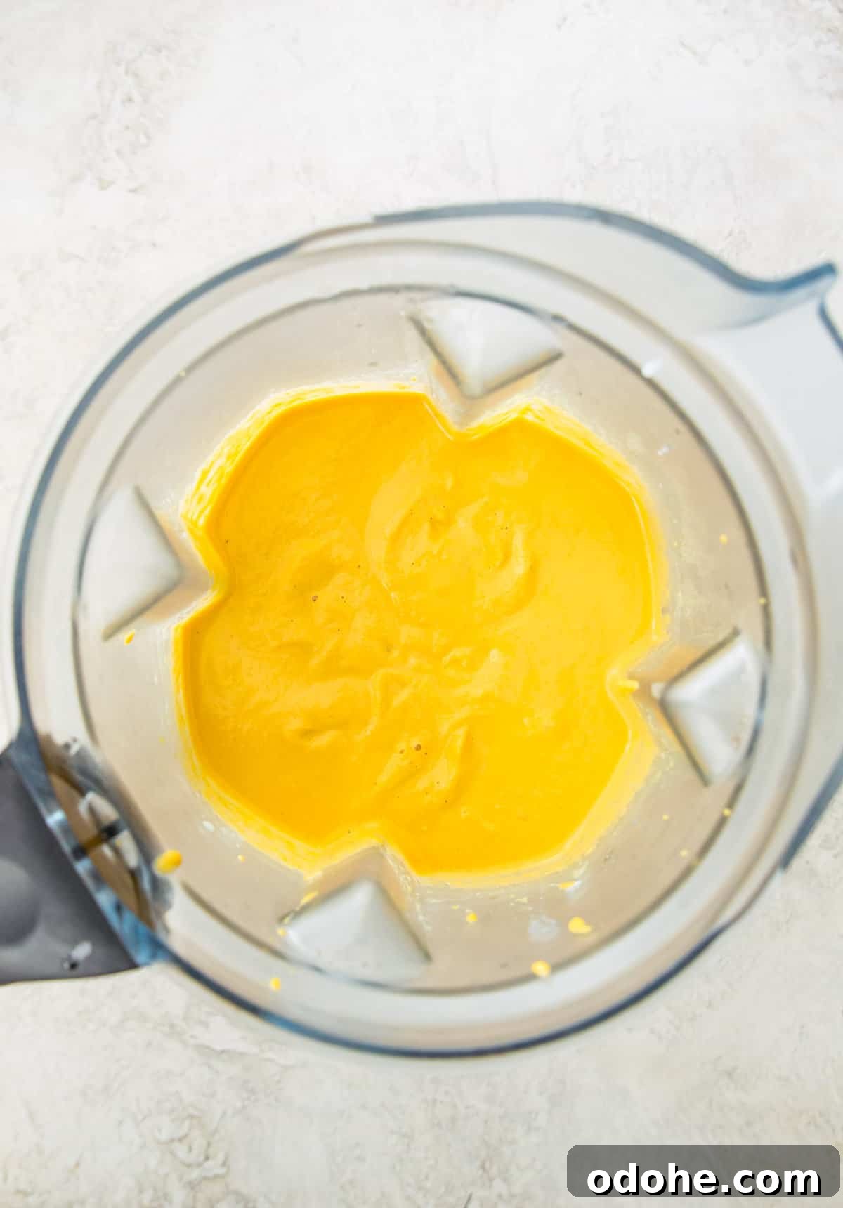 A blender with a cheese sauce in it.