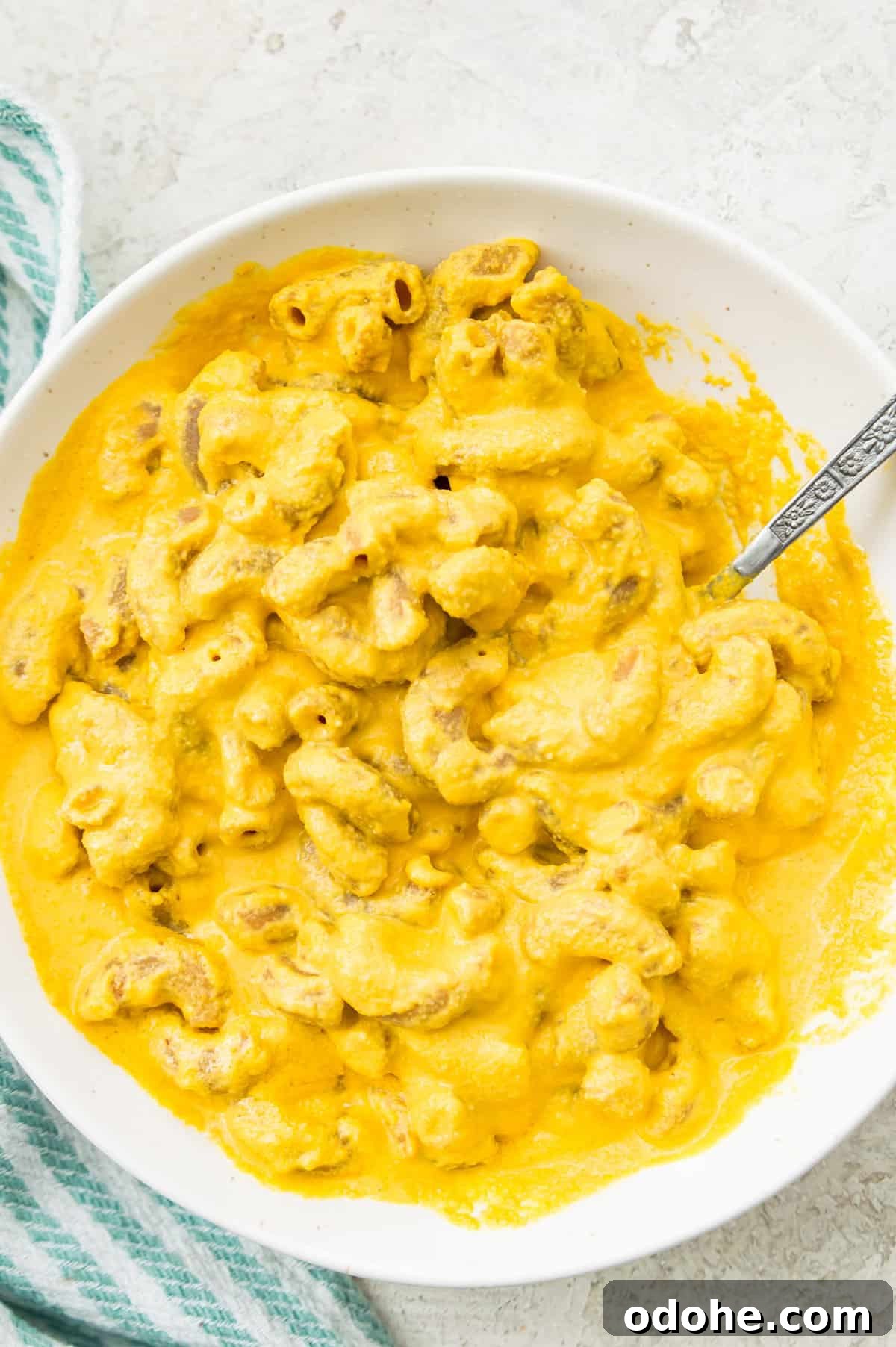 A bowl of macaroni and cheese with a spoon in it. 