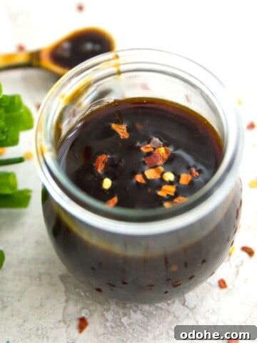 A jar of teriyaki sauce with chili flakes on it.