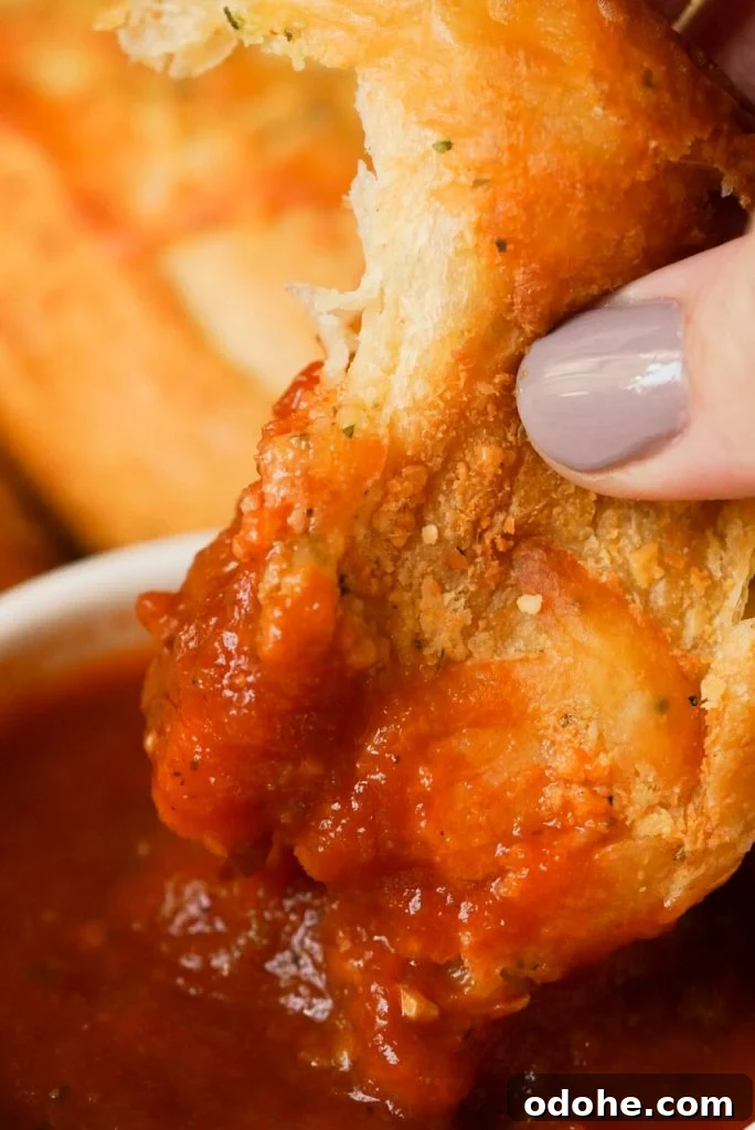 a crescent roll garlic knot dipped in marinara sauce