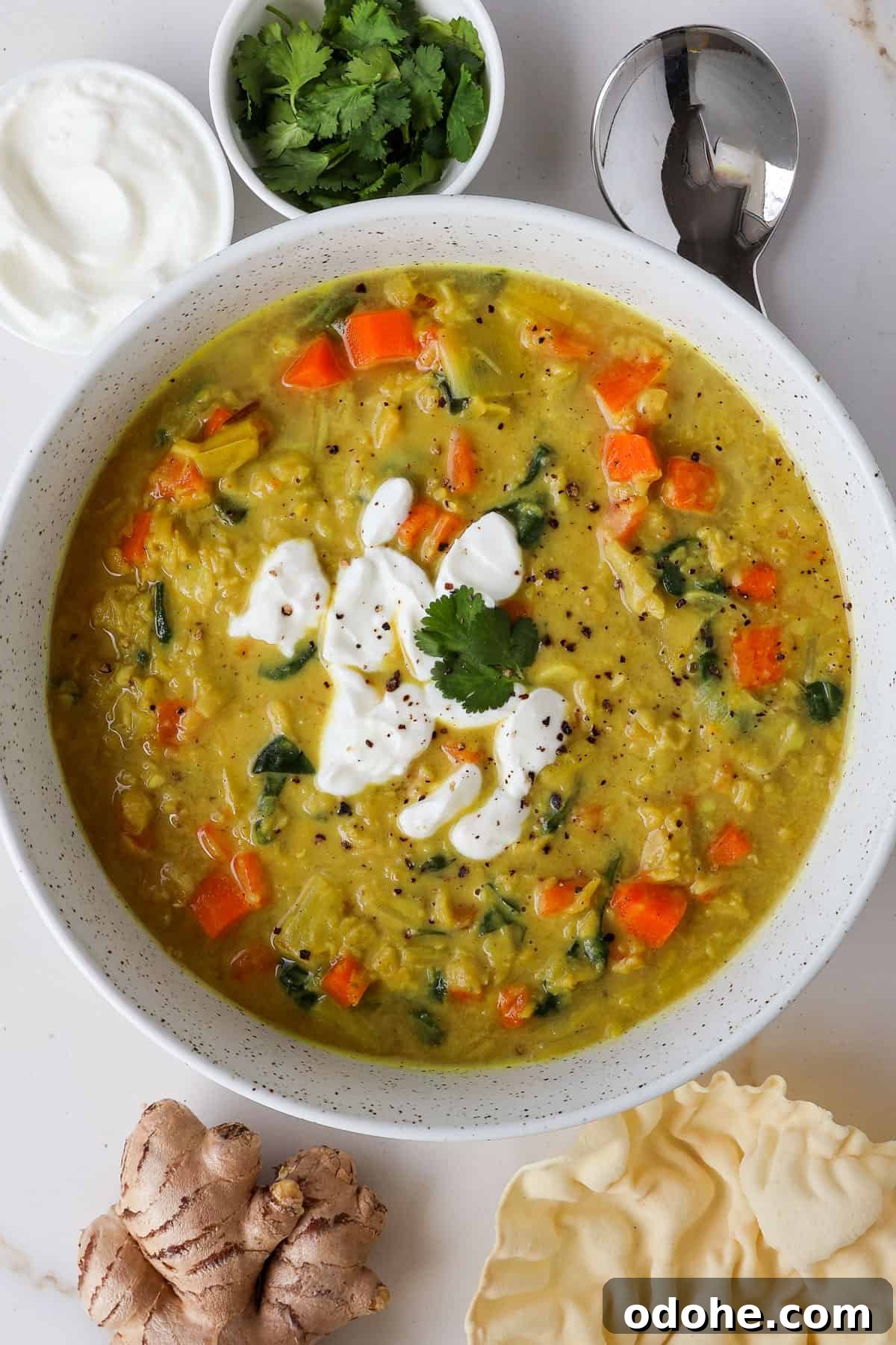 Carrot and lentil soup in a bowl topped with yoghurt and coriander.