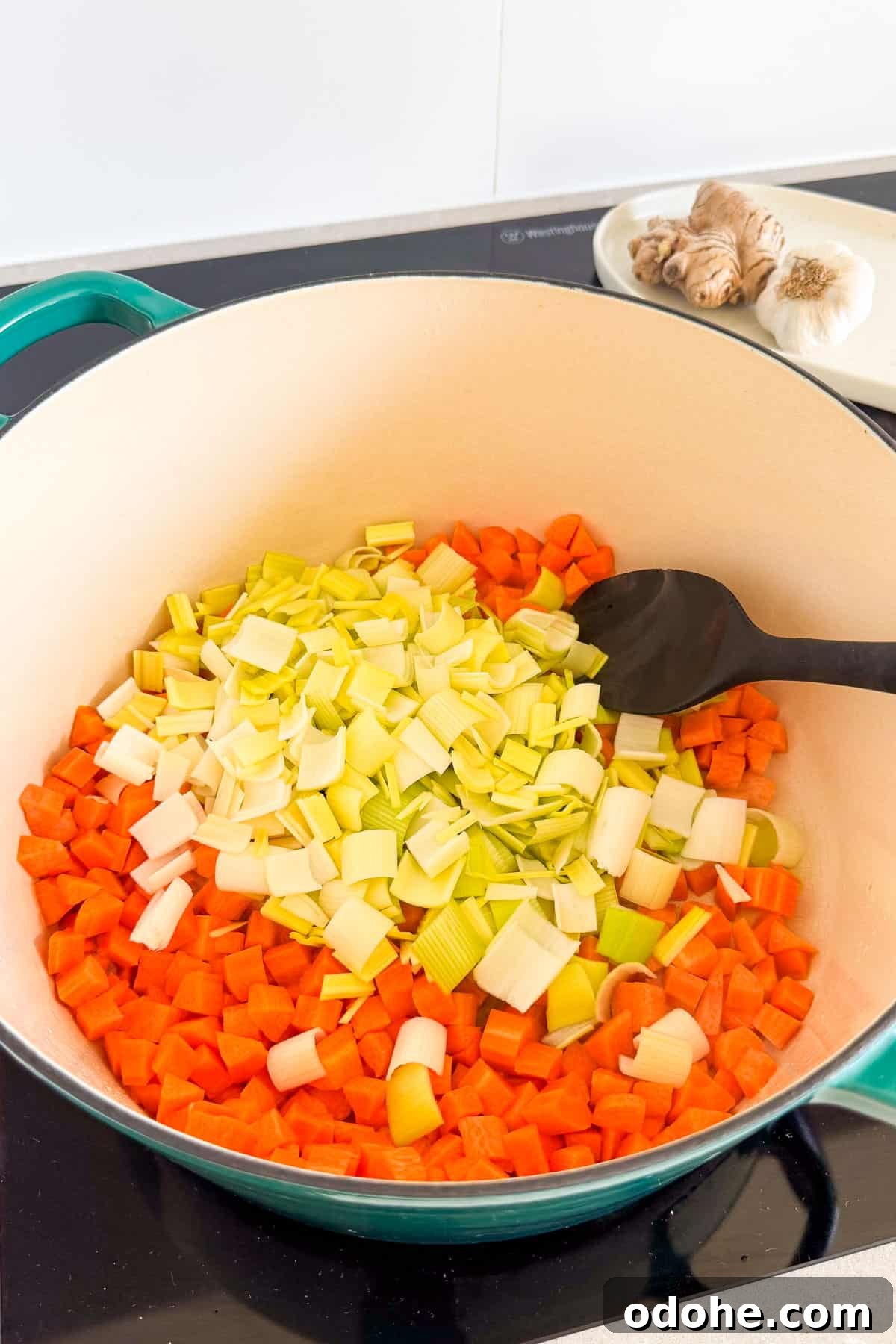 Carrots and leeks being sautéed in a pot.