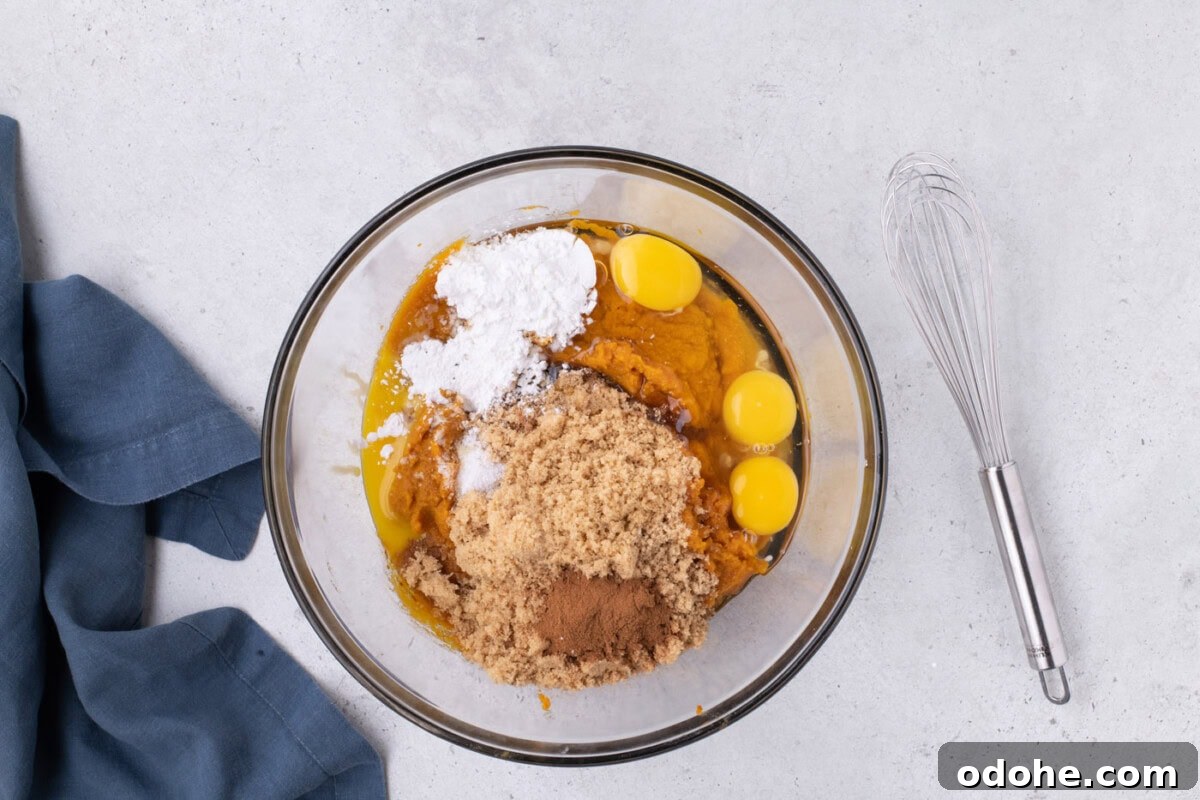 Giant Pumpkin Slab Pie Recipe for Fall Gatherings 11 pumpkin puree, brown sugar, egg, egg yolk, cornstarch, and pumpkin pie spice in a bowl