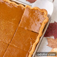 Giant Pumpkin Slab Pie Recipe for Fall Gatherings 18 Pumpkin Slab Pie cut into squares with a spatula removing a piece