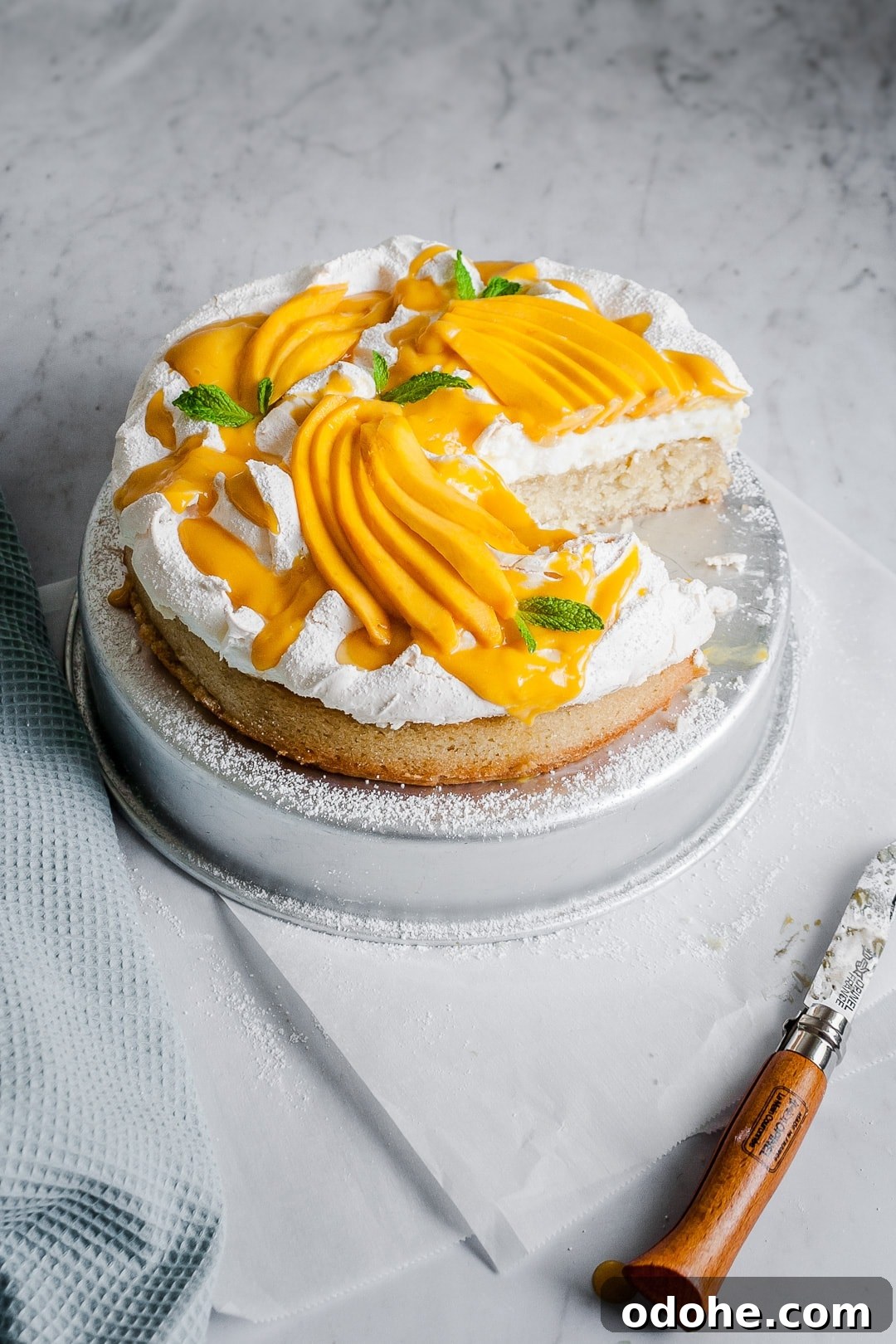 Angled view of coconut meringue cake with slices missing on a marble background