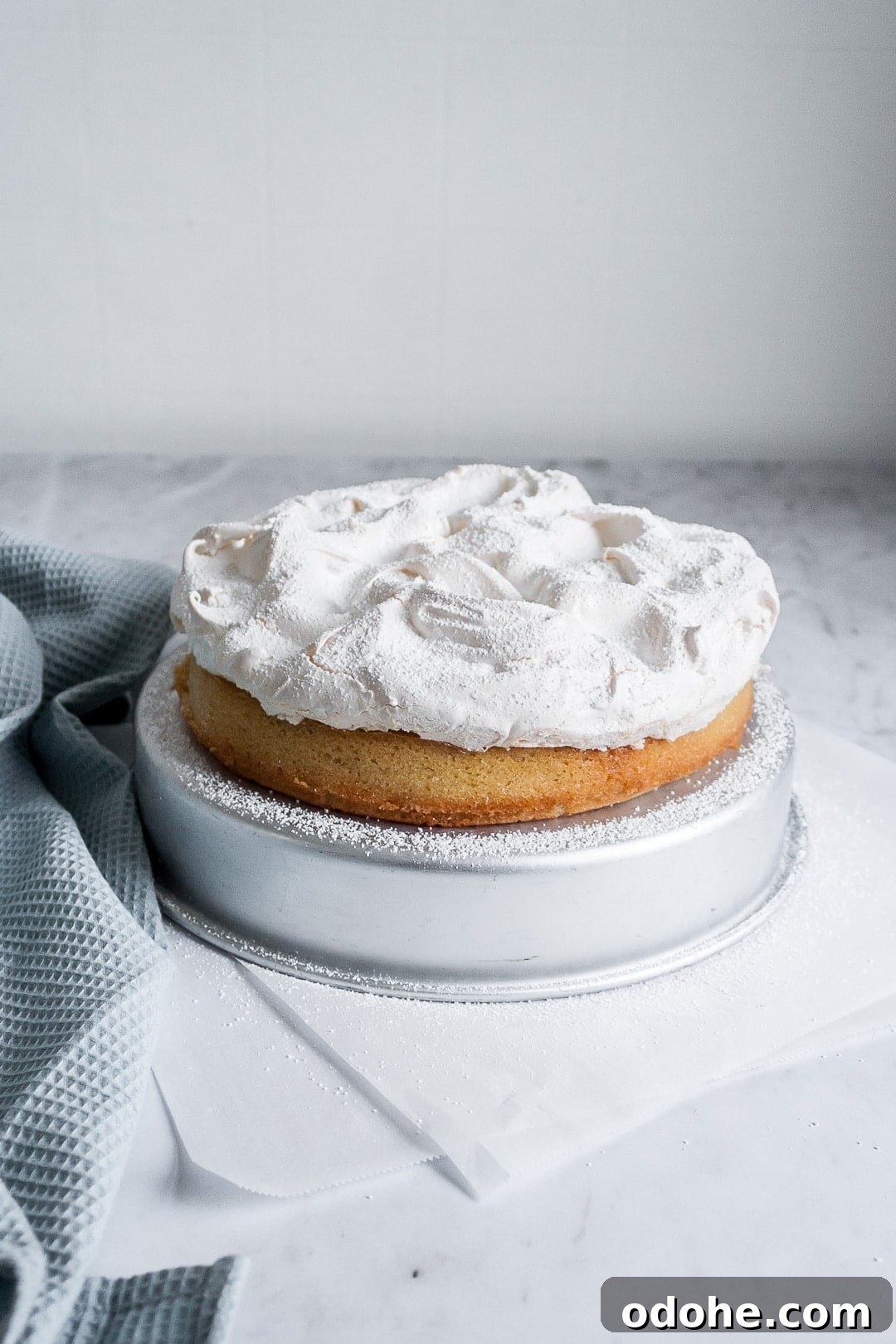 45 degree angle view of coconut cake with baked meringue layer on top on a marble background