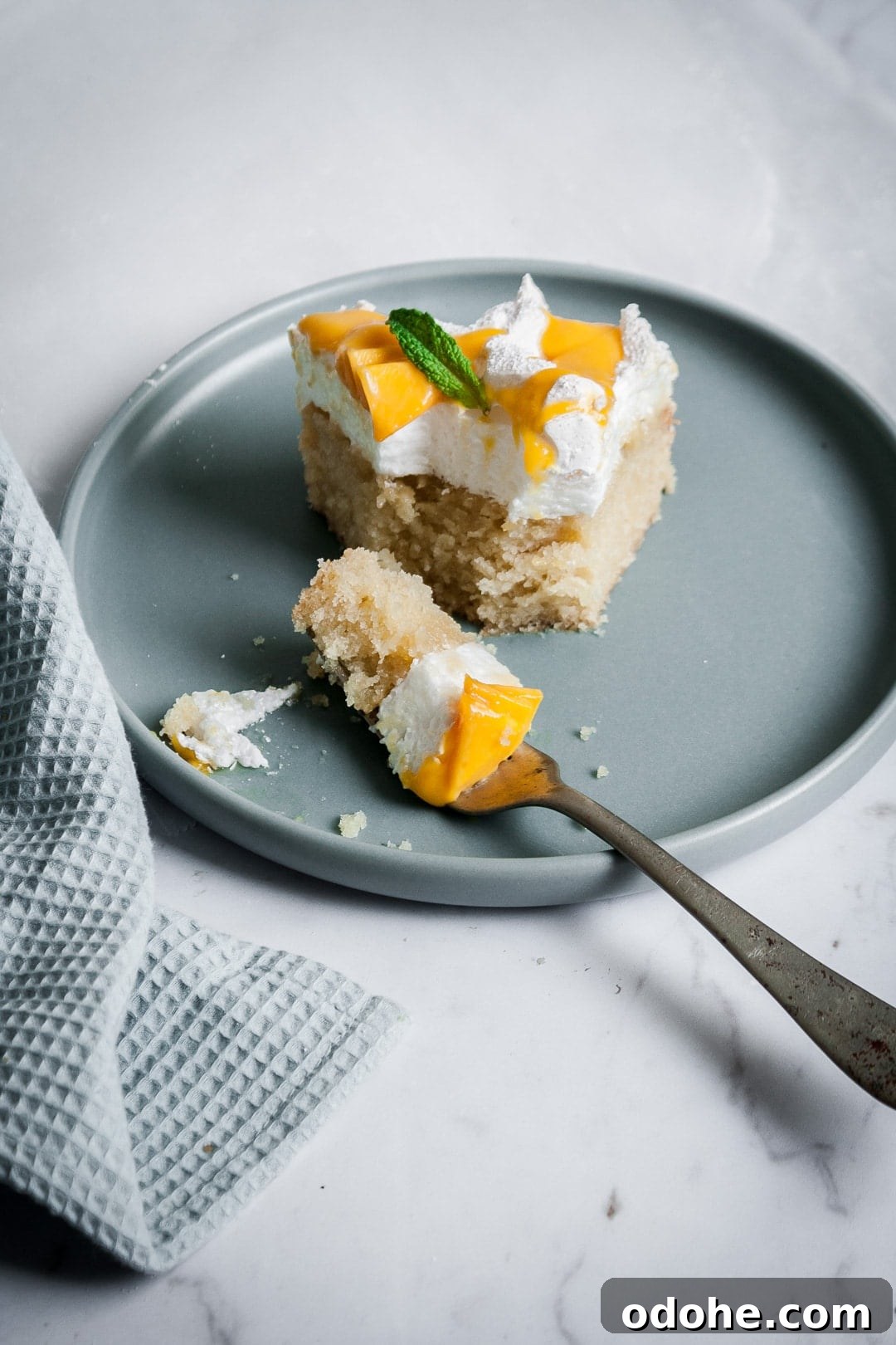 Partially eaten slice of coconut meringue cake on a blue plate