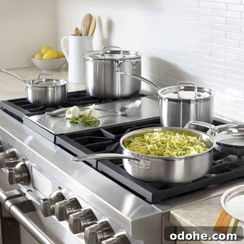 A set of Cuisinart stainless steel pots and pans on a stovetop.
