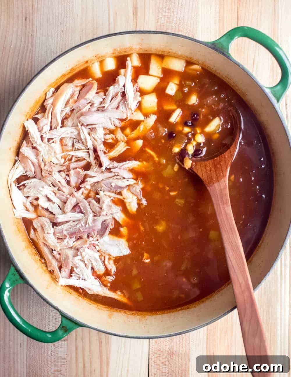 Authentic Mexican Tortilla Soup Recipe with Crispy Tortilla Strips 4 Shredded chicken being added to a pot of tortilla soup