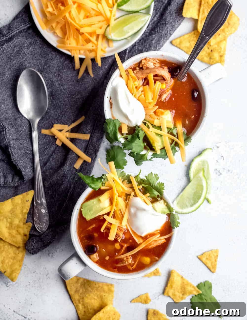 Authentic Mexican Tortilla Soup Recipe with Crispy Tortilla Strips 8 Two white mugs filled with tortilla soup and topped with cheese, avocado, sour cream and cilantro