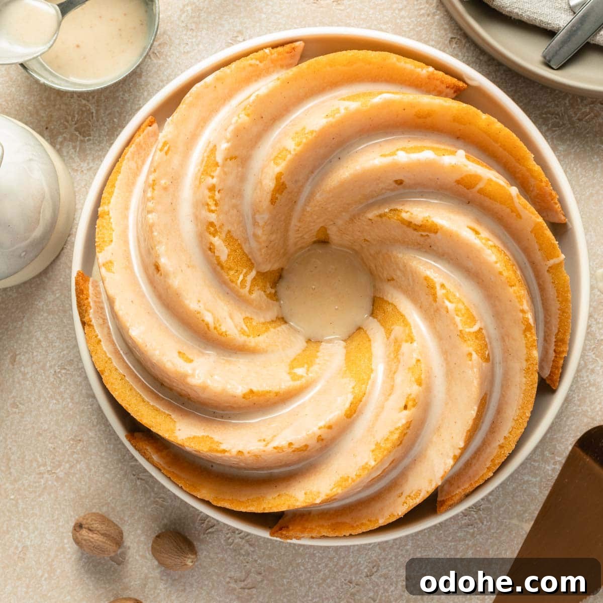 Decadent Eggnog Bundt Cake Recipe for Holiday Gatherings 8 Overhead view of an eggnog bundt cake topped with glaze on a round plate.