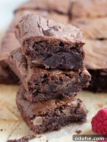 A stack of air fryer chocolate brownies with raspberries on the side.