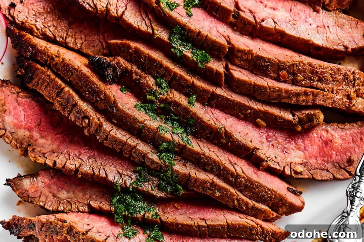 Orange and lime juice, garlic and jalapeno, maple and cumin - this easy Grilled Carne Asada is drenched in a medley of mouthwatering flavors! Close up shot of sliced flank steak, showing the texture and medium-rare doneness of the meat.