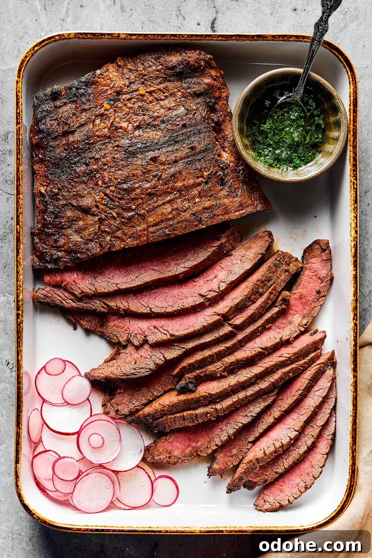 Orange and lime juice, garlic and jalapeno, maple and cumin - this easy Grilled Carne Asada is drenched in a medley of mouthwatering flavors! Grilled flank steak, partially sliced into thin strips, with a cup of dipping sauce on one side and a sliced radish on the other.