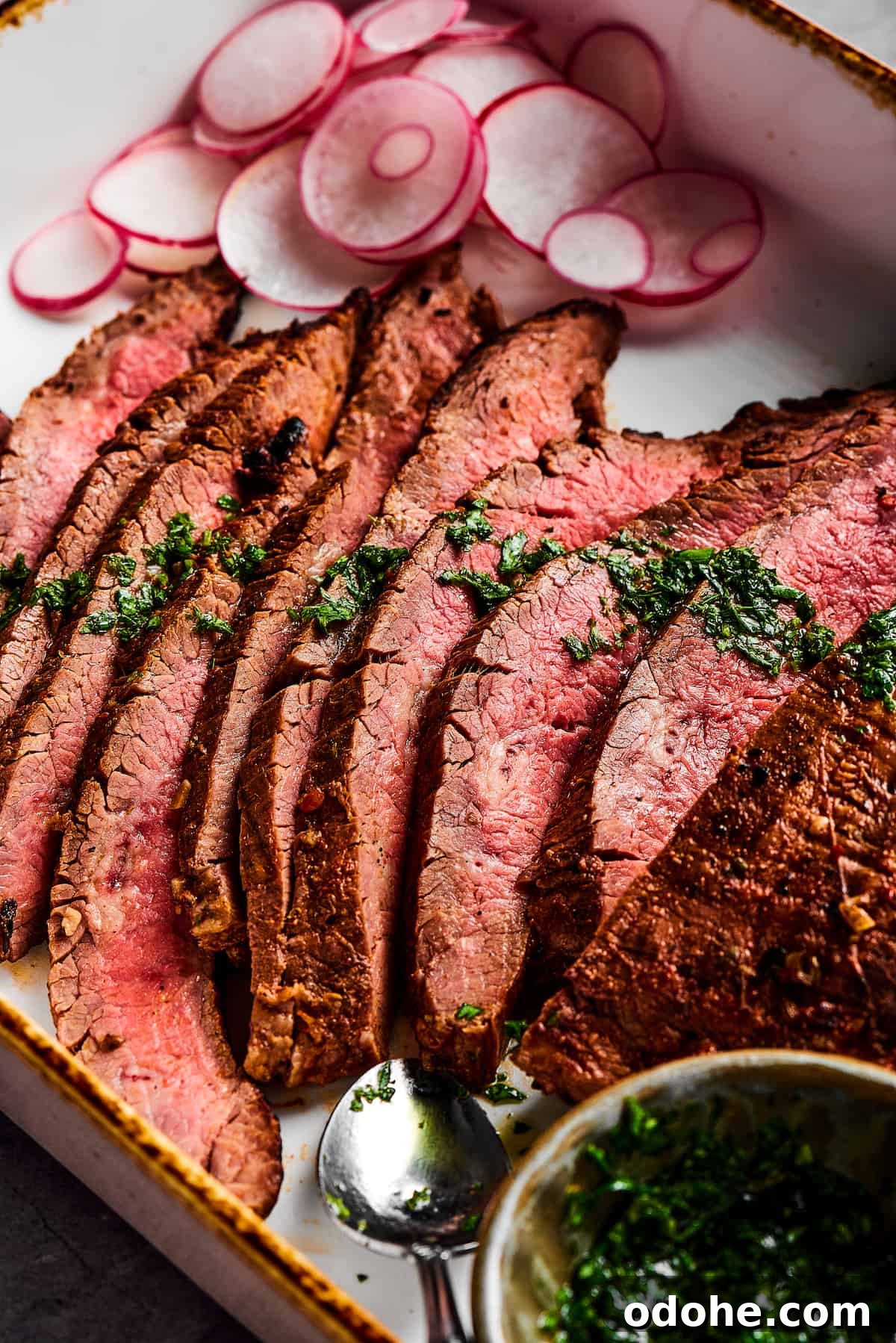 Orange and lime juice, garlic and jalapeno, maple and cumin - this easy Grilled Carne Asada is drenched in a medley of mouthwatering flavors! Slices of steak next to a cup of herb sauce.