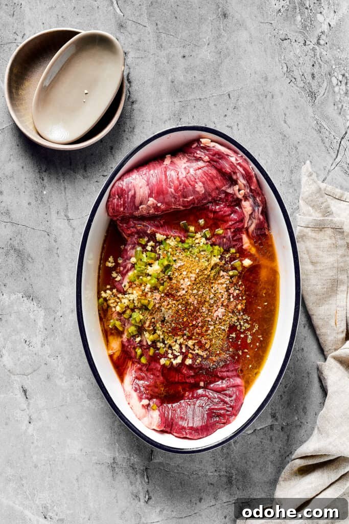 Grilled Carne Asada Recipe for Tender, Flavorful Steak 2 A flank steak in an enamel oval dish, covered in marinade.