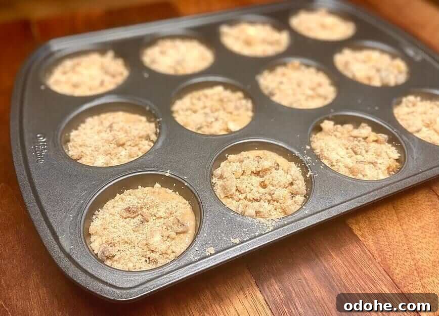 Streusel topping sprinkled on top of muffin batter in pan.