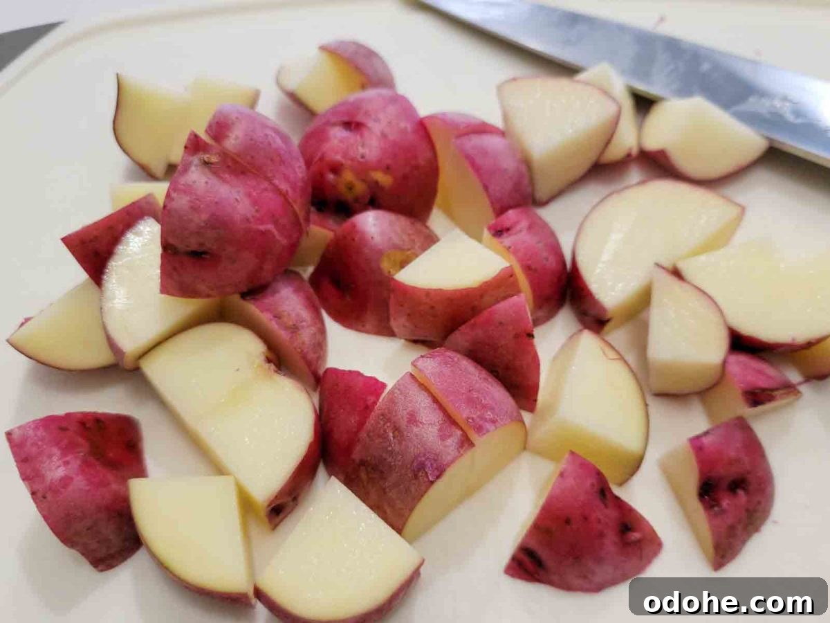 Italian Sheet-Pan Dinner: Simple One-Pan Tray Bake Recipe 3 red skin potatoes cut into pieces on a cutting board.