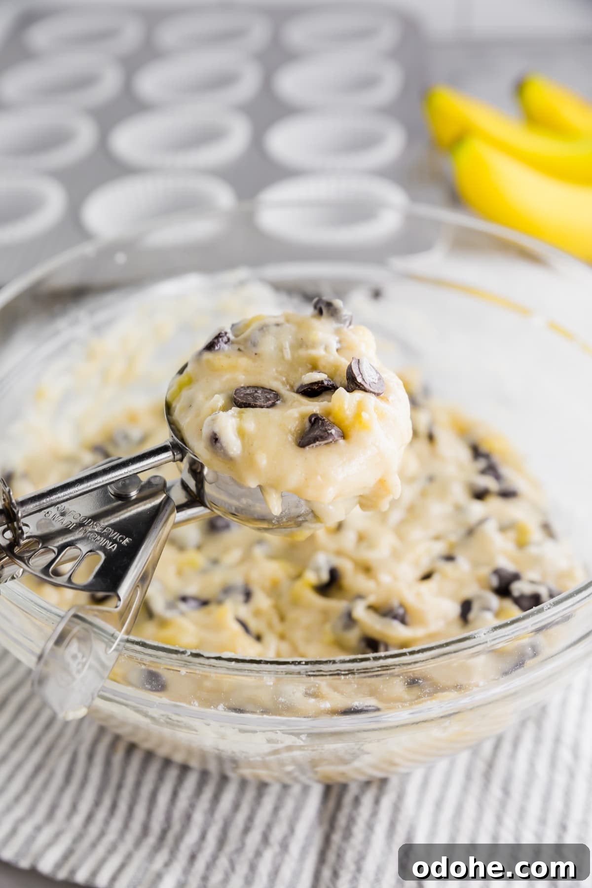 Gluten-Free Vegan Banana Chocolate Chip Muffins Recipe 6 A cookie scoop with banana chocolate chip muffin batter in it ready to portion into a muffin tin.