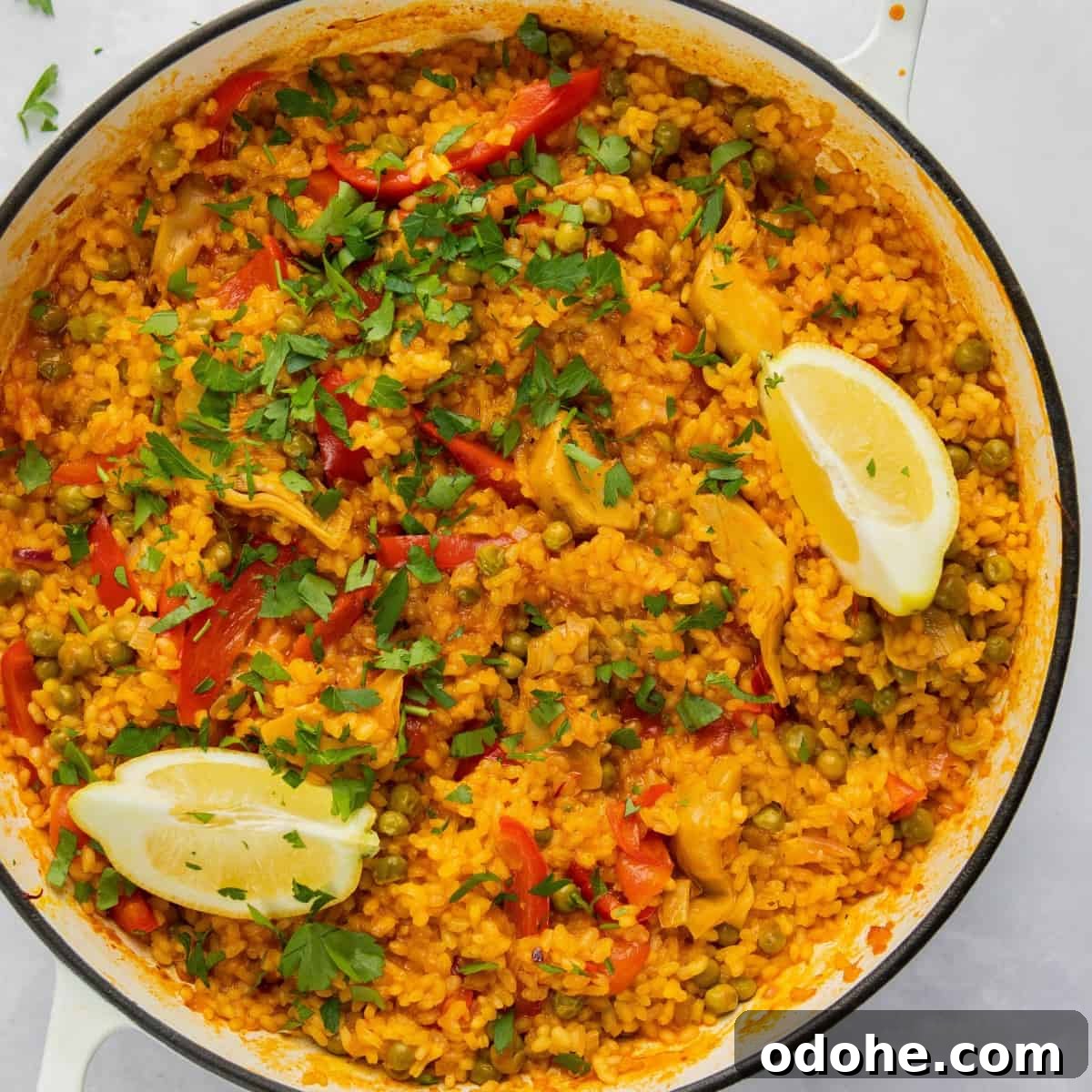 overhead shot of paella on pan with wedges of lemon. 