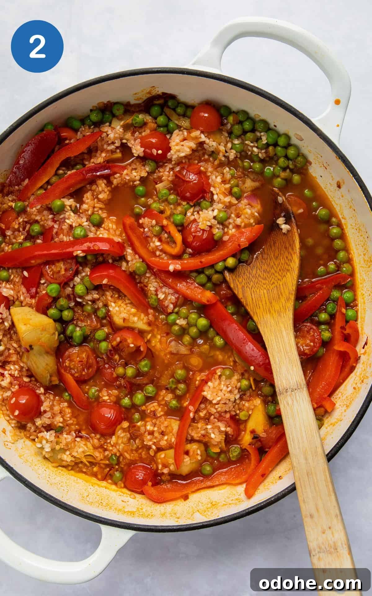 ingredients to make paella in large shallow white frying pan.