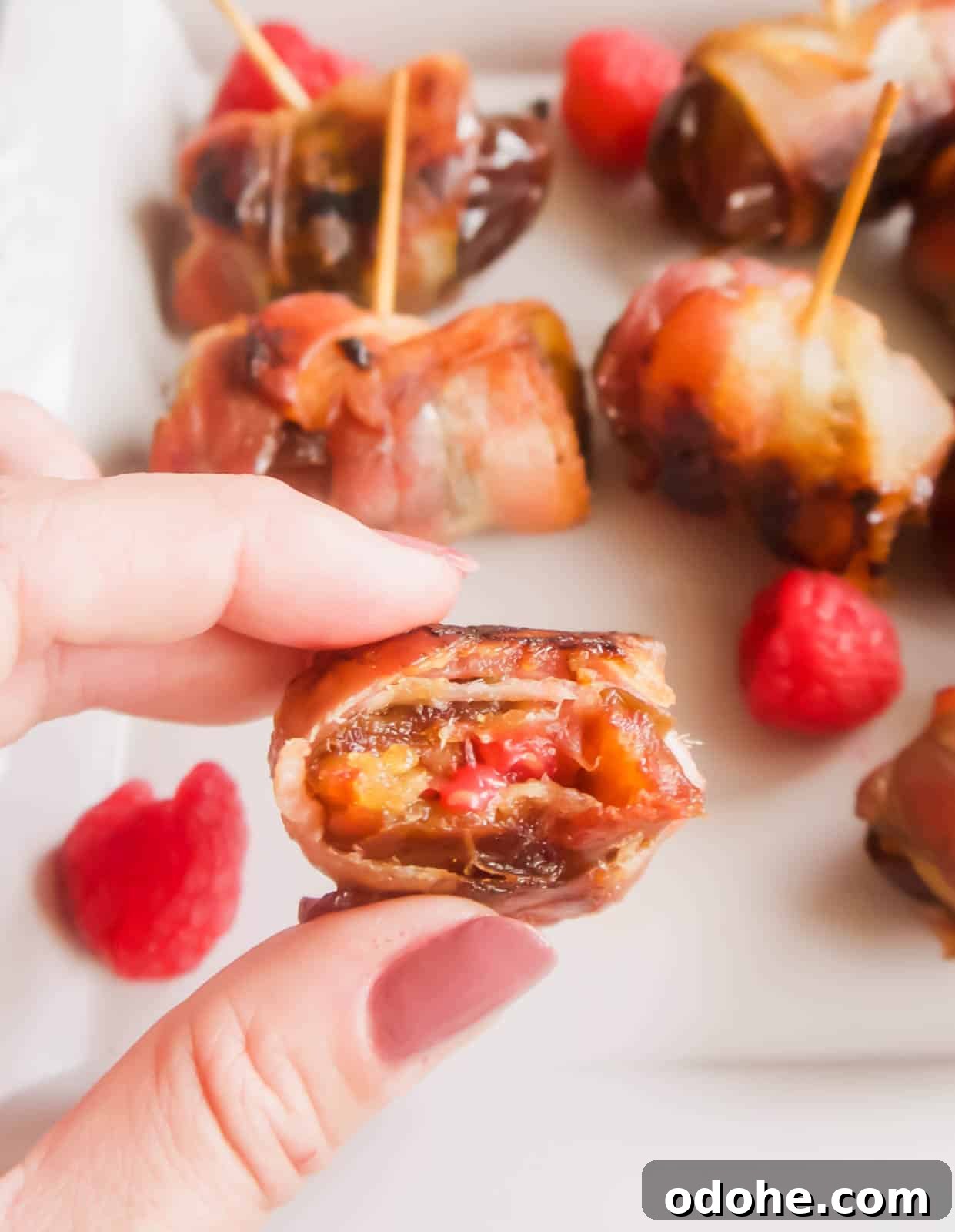 Bacon-Wrapped Raspberry-Stuffed Dates | Paleo & Whole30-Friendly 9 A bite taken out of a date with raspberries inside.