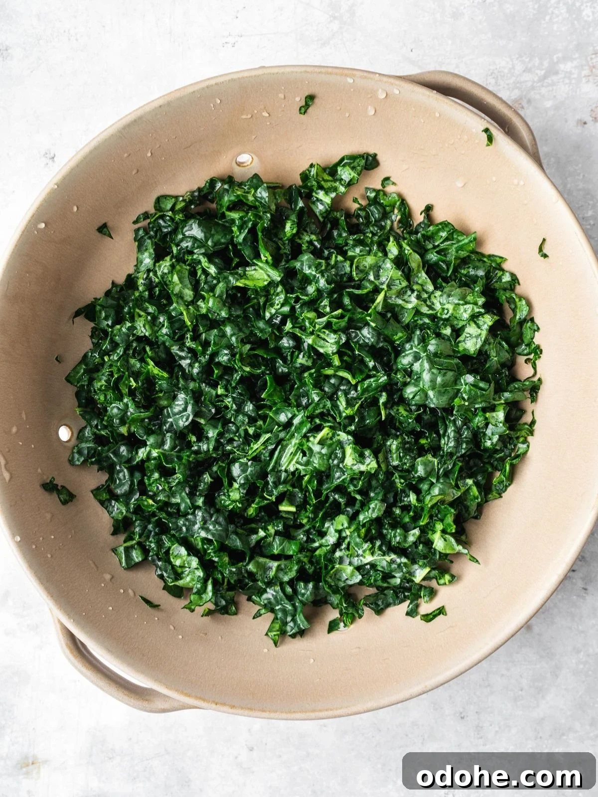 A colander filled with chopped, dark green kale.