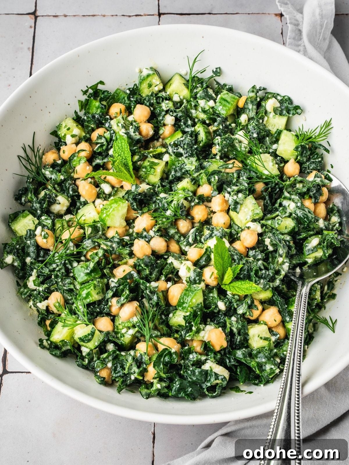 A bowl of Kale Chickpea Feta Salad with chopped kale, chickpeas, cucumber, fresh mint, dill, and a creamy dressing, garnished with feta.