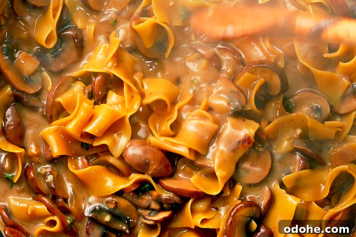 Stirring noodles in skillet for one pot mushroom stroganoff.