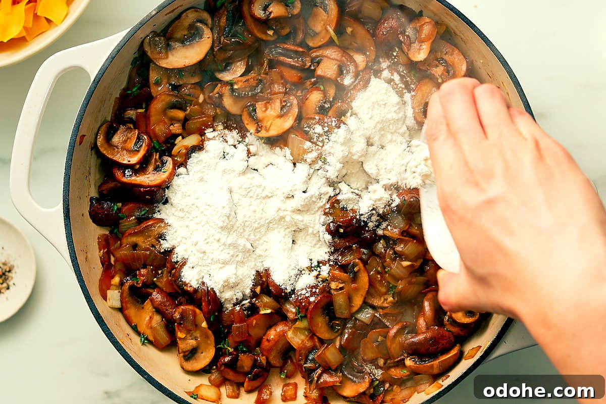 Adding flour to sauteed mushrooms in a skillet for vegetarian Mushroom Stroganoff.