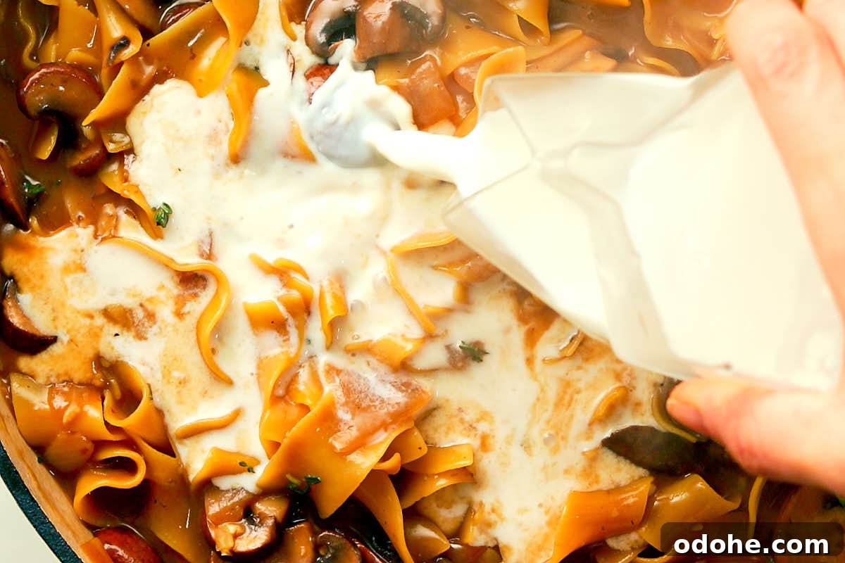 Pouring milk into a skillet of one pot Mushroom Stroganoff.
