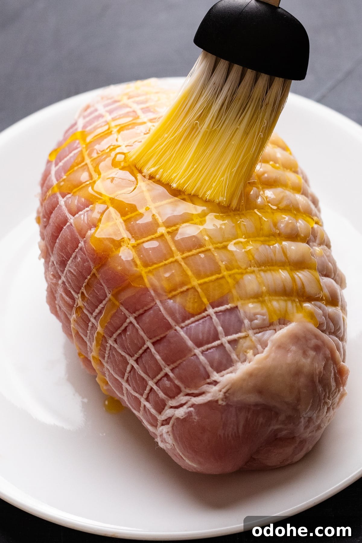 Maple Herb Turkey Breast in the Air Fryer: Juicy, Flavorful Roast 5 A brush basting melted butter on a turkey breast that's sitting on a white plate.