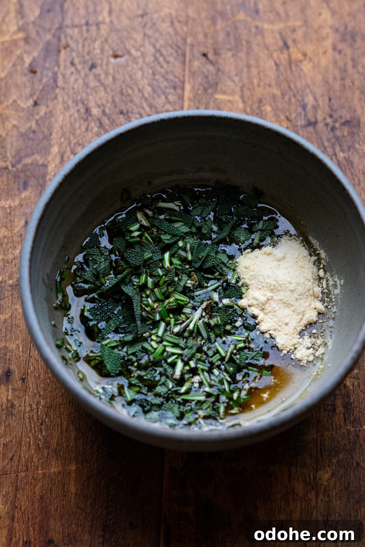 Maple Herb Turkey Breast in the Air Fryer: Juicy, Flavorful Roast 6 A gray bowl with chopped herbs, onion powder, and maple syrup in it sitting on a brown board.