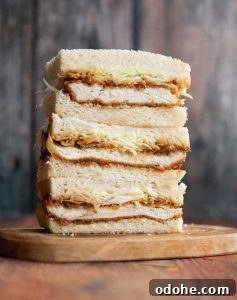 3 sandwich thirds stacked on each other on small wooden board
