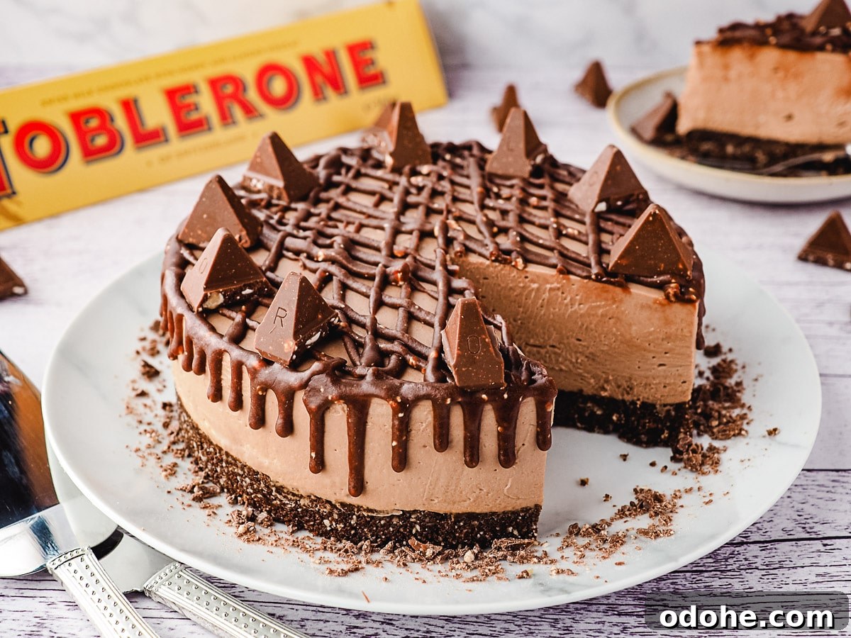 No-Bake Cheesecake Recipes: Simple, No-Oven Dessert Ideas 14 Whole cheescake on a plate, with slice on a plate and Toblerone in background.