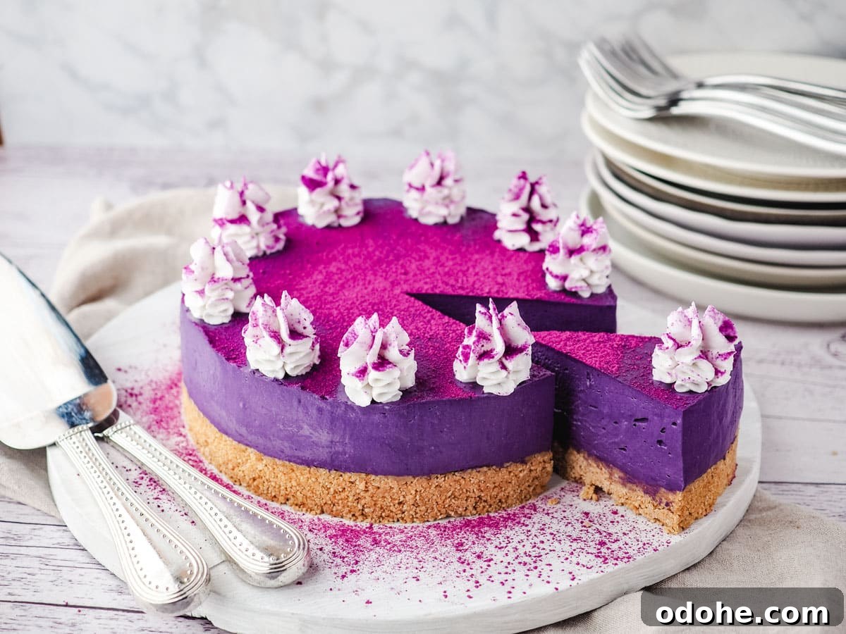 No-Bake Cheesecake Recipes: Simple, No-Oven Dessert Ideas 31 Sliced ube cheesecake on a serving board, with utensile on the side and a stack of plates and forks in the background.