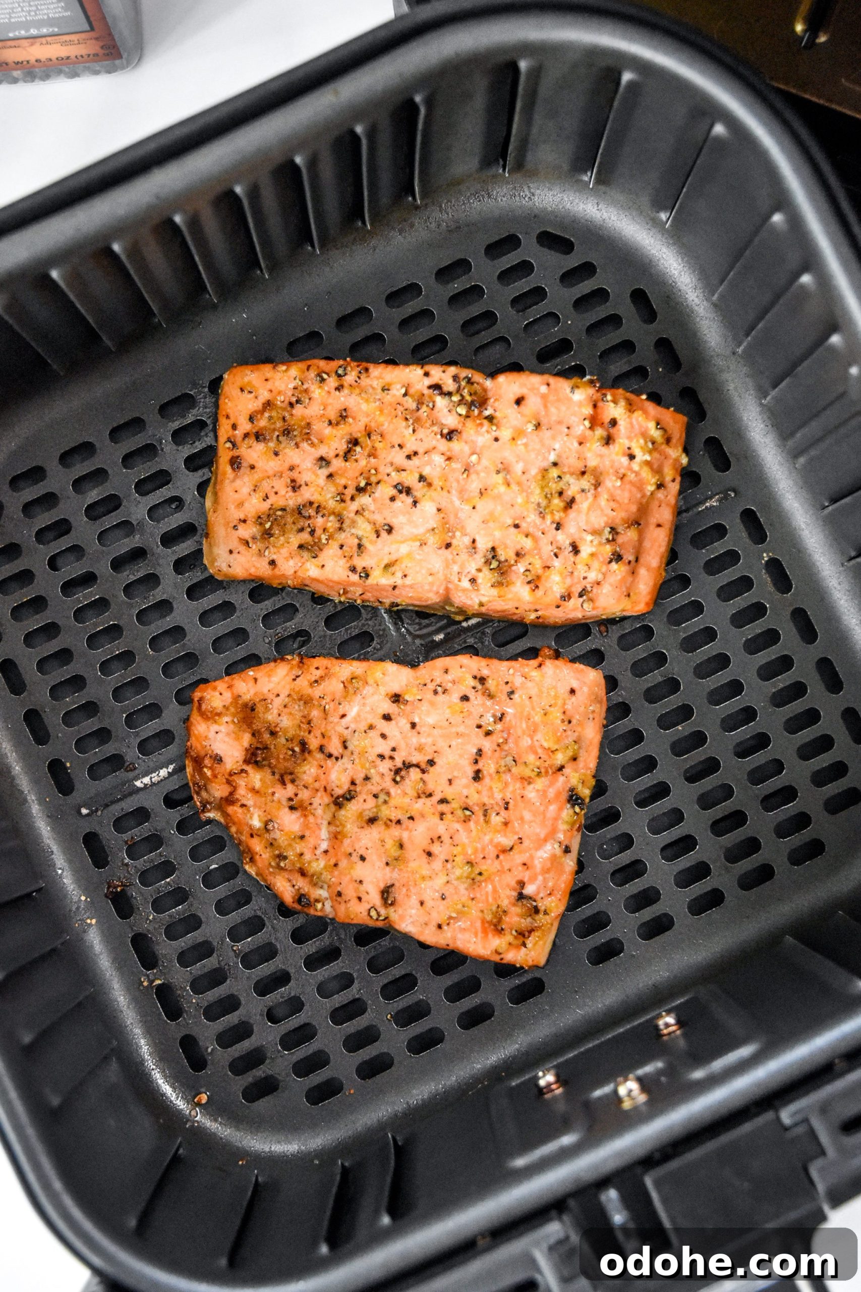 cooked air fryer lemon pepper salmon in the air fryer basket.