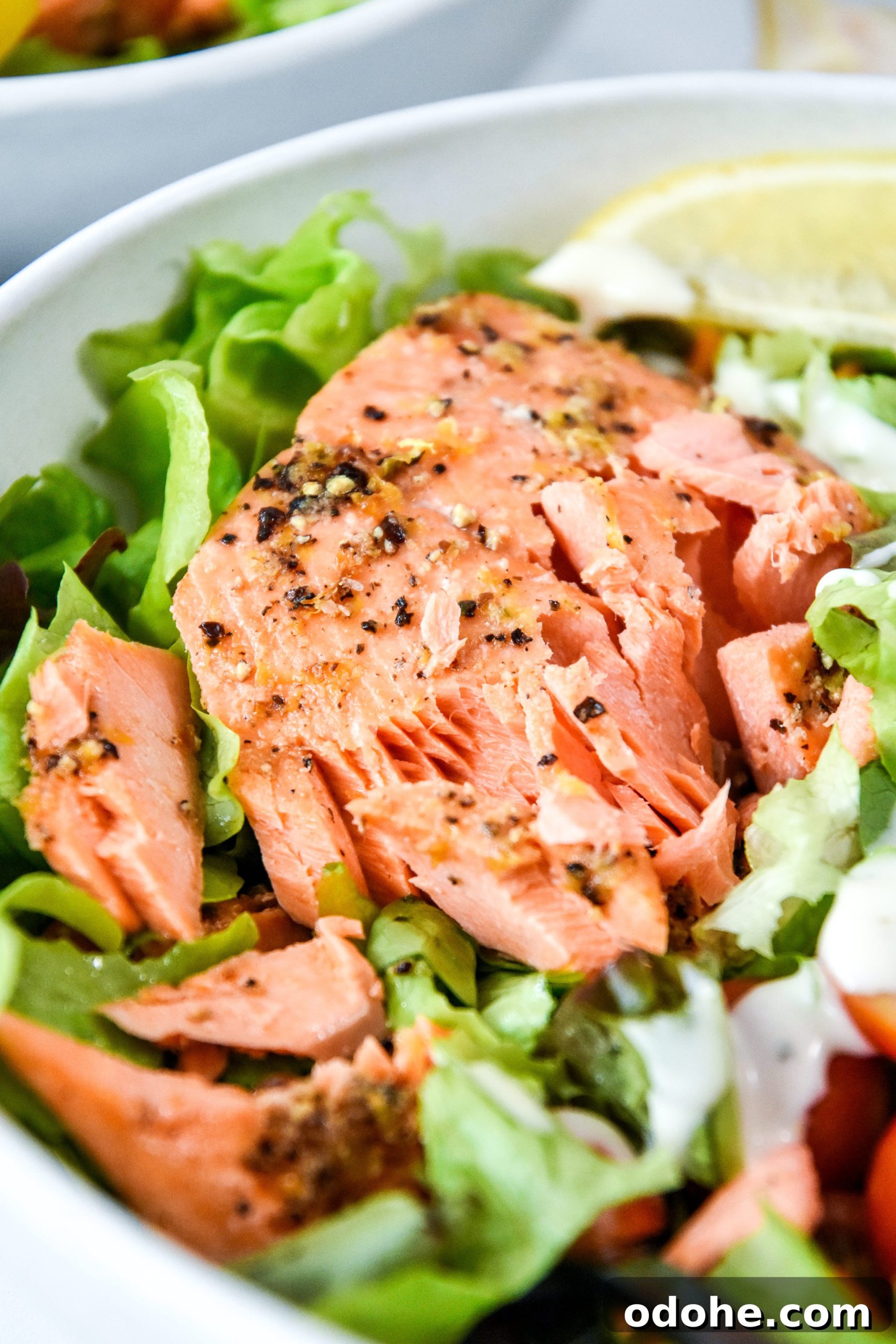 air fryer lemon pepper salmon flaked apart on a salad.