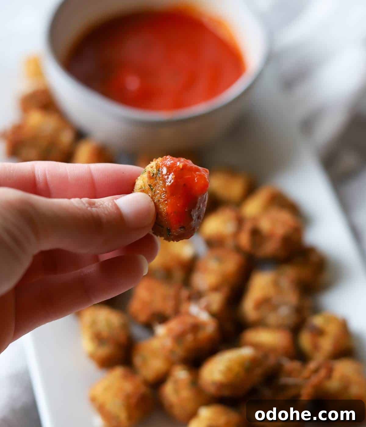 Crispy Fried Mozzarella Balls with Marinara Dip 4 Hand holding marinara dipped mozzarella.