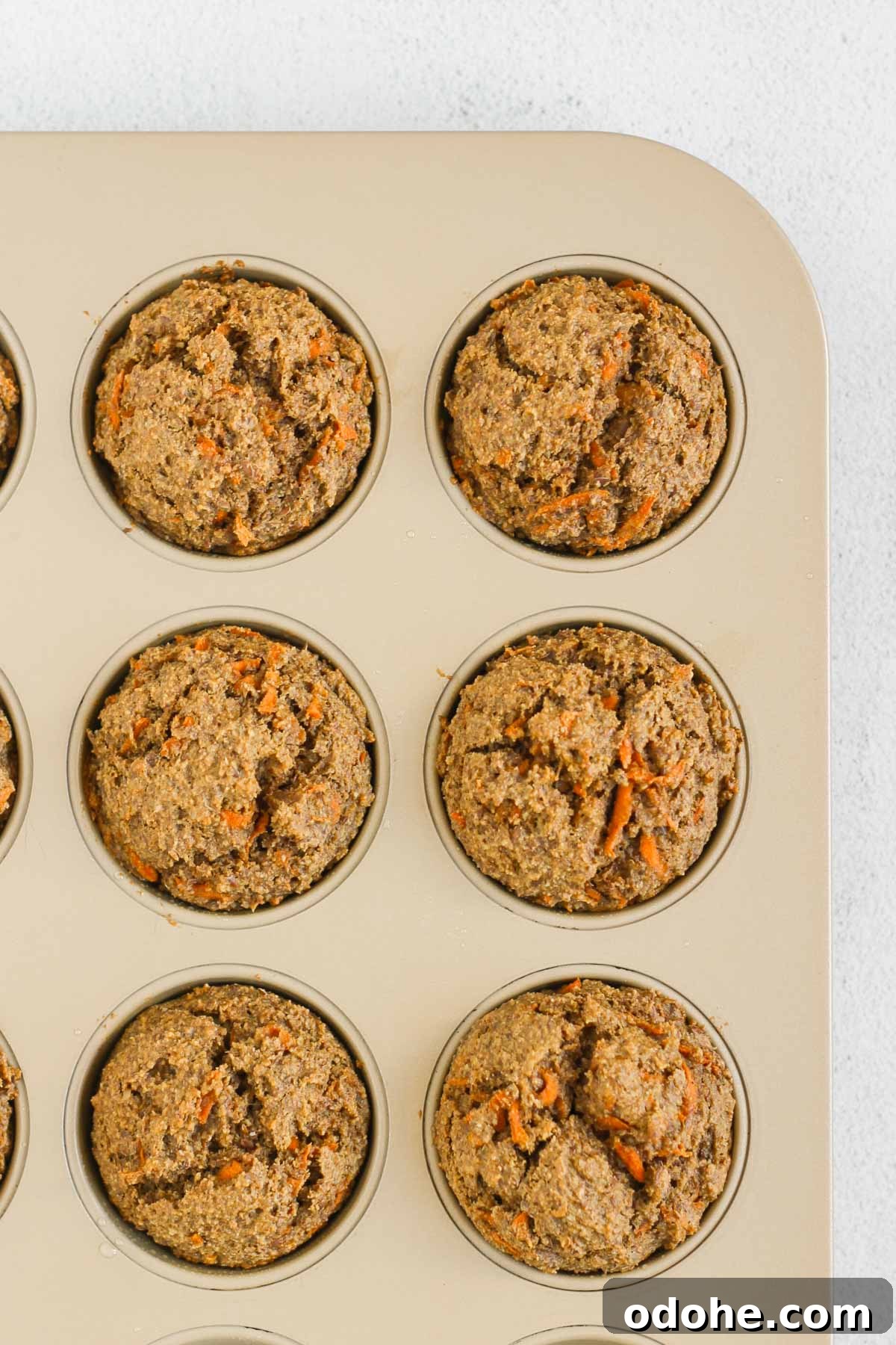 Flaxseed Carrot Muffins with Cinnamon and Honey 8 Baked carrot flaxseed muffins in a muffin tin.