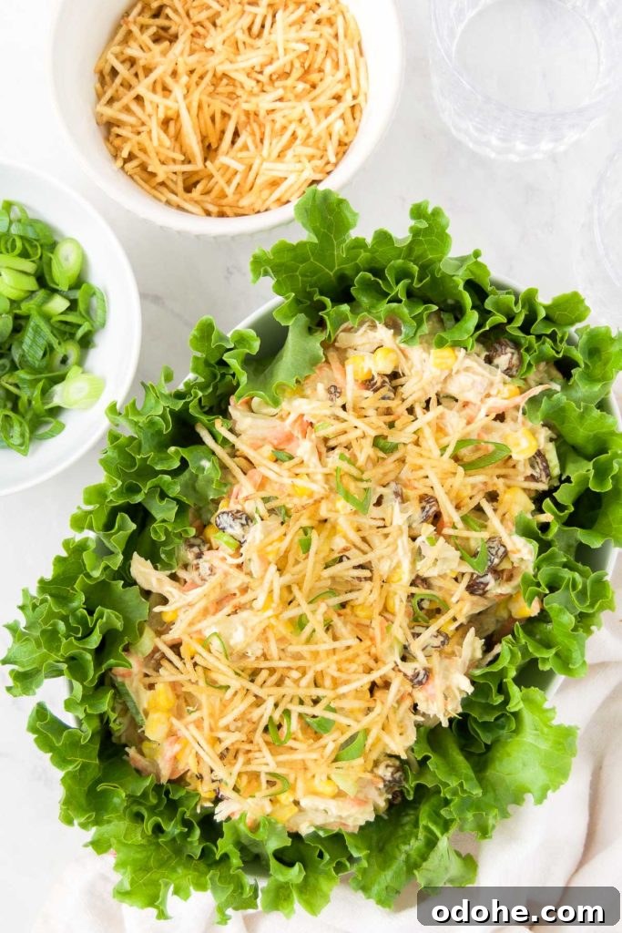Brazilian chicken salad in a serving dish, surrounded by salad greens