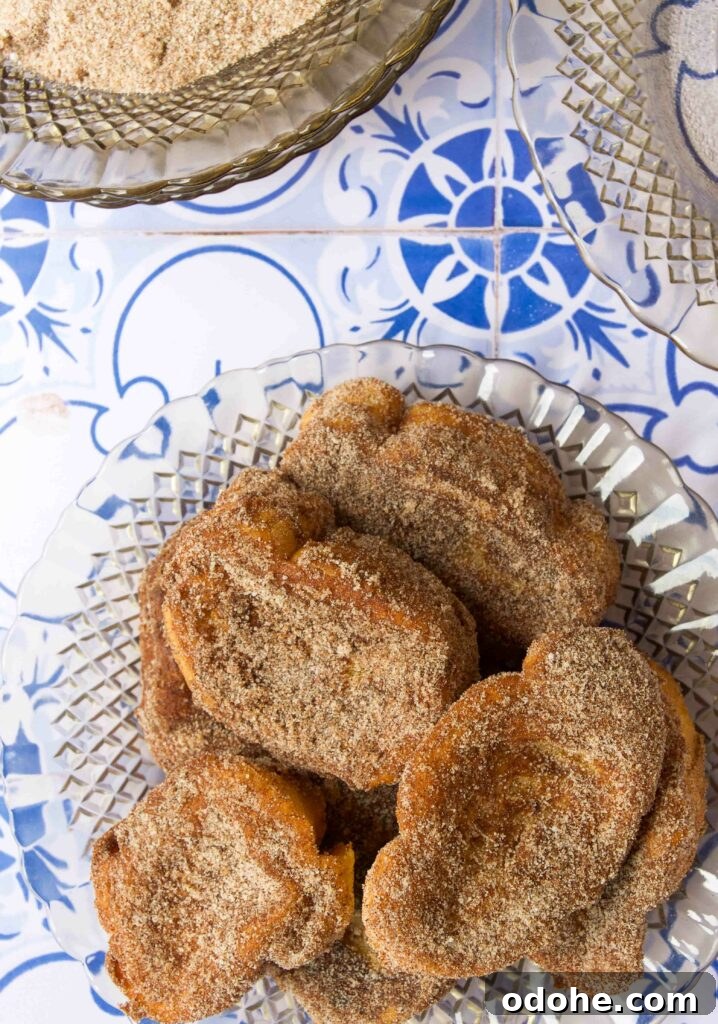 Pieces of cinnamon-sugar coated Rabanada on a glass plate on a blue tile countertop