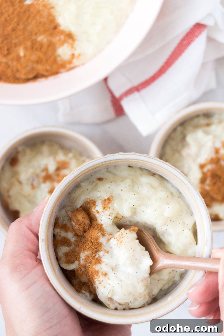 A person holds a bowl of Brazilian Rice Pudding with a spoon