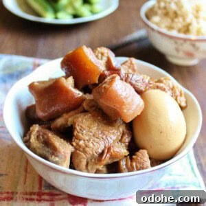 Vietnamese Braised Pork and Eggs (Thịt Kho Trứng) 6 Vietnamese Braised Pork with Egg in a bowl, a rice bowl is in the back along with a plate of cucumber.