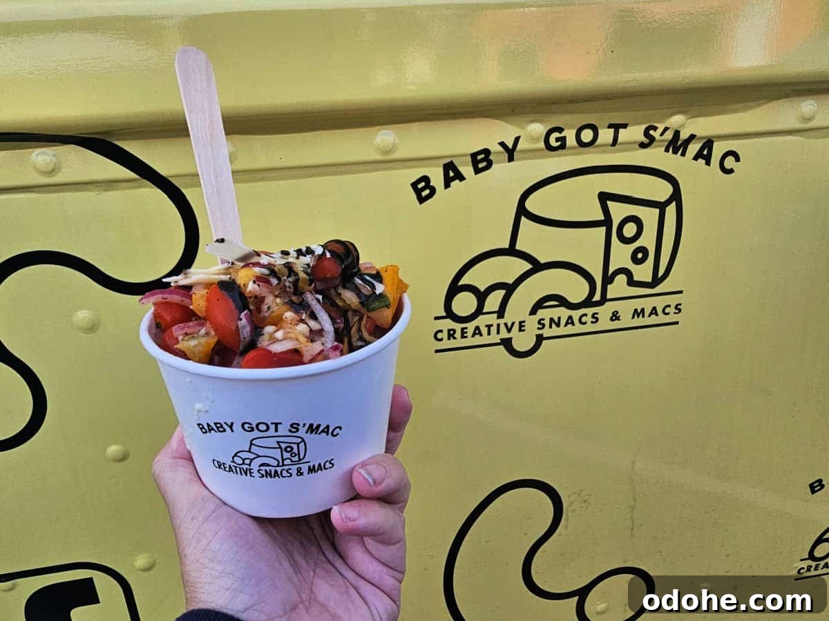 hand holding a cup of Italia Mac in front of the Baby Got S'Mac yellow logo