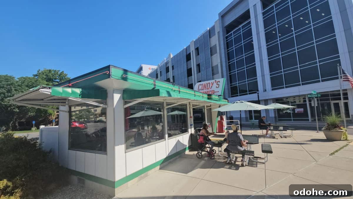 Cindy's Diner sign over the exterior of a white and green building with tables with green umbrellas outside